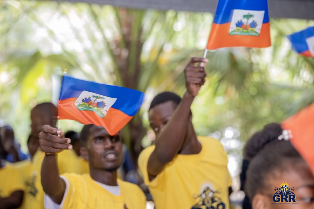 Des membres de la GRR agitent des drapeaux haïtiens lors d'un rassemblement en plein air.